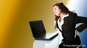 a person Toronto bending over a computer holding her back due to pain